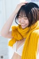 A woman wearing a yellow scarf smiles at the camera.