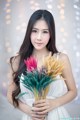 A woman in a white dress holding a bunch of flowers.