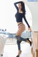 A woman in fishnet stockings and high heels posing on a bed.