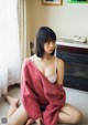 A woman sitting on the floor in a pink sweater.