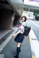 A woman in a school uniform is walking down the street.