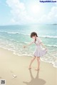 A girl in a white dress standing on a beach.