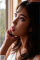 A woman with long brown hair looking out a window.