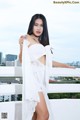 A woman in a white dress posing on a balcony.